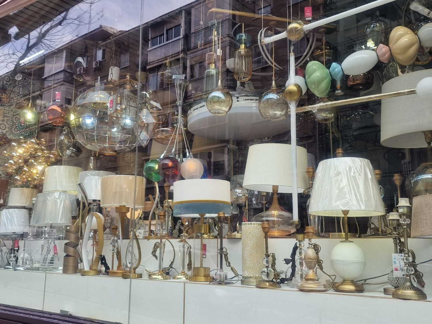 En el escaparate de una tienda se exhibe una colección de diversas lámparas de mesa y lámparas colgantes.
