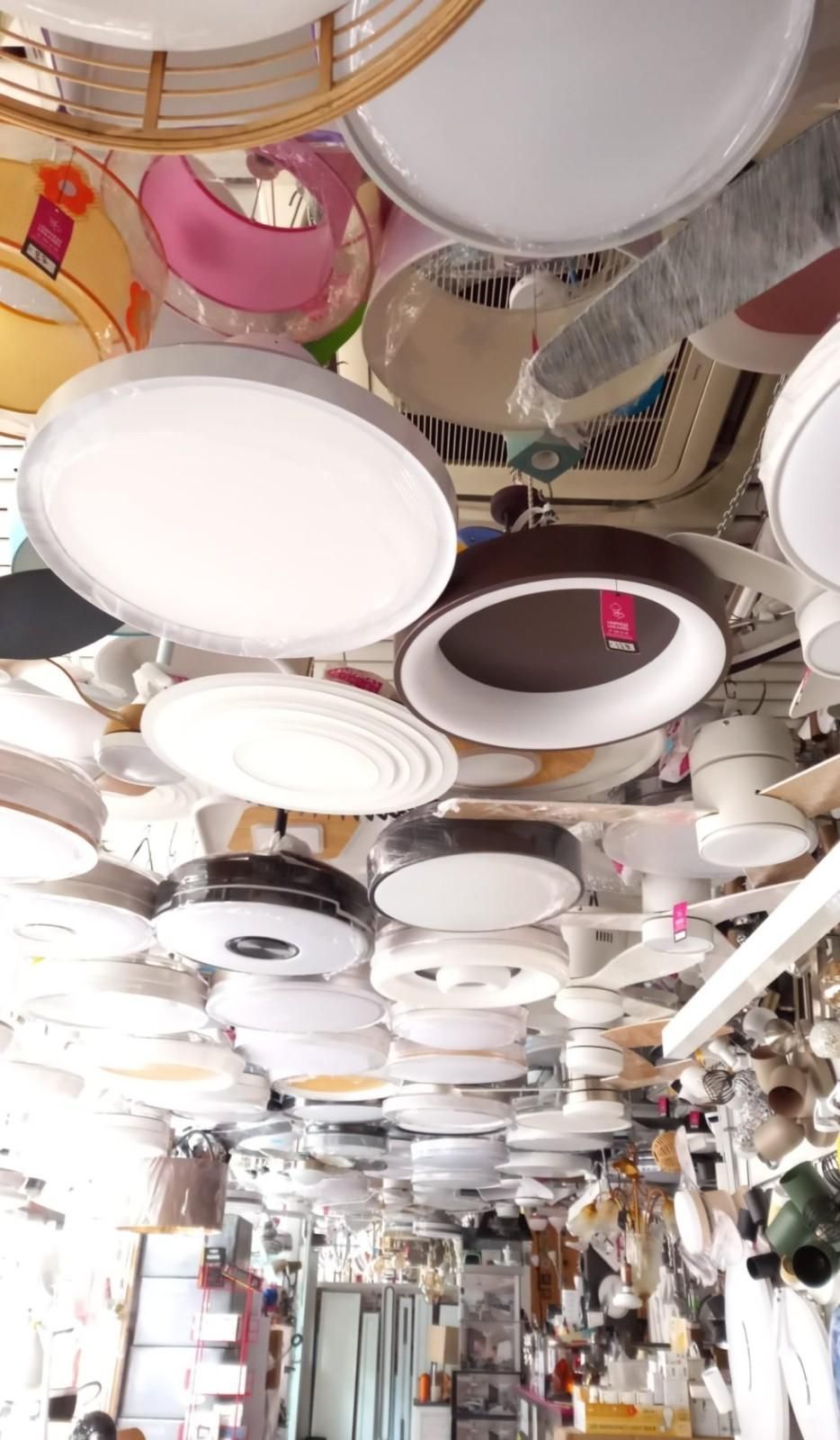 Vista desde un ángulo bajo de numerosas luces LED circulares colgadas muy juntas en el techo de una luminosa tienda.