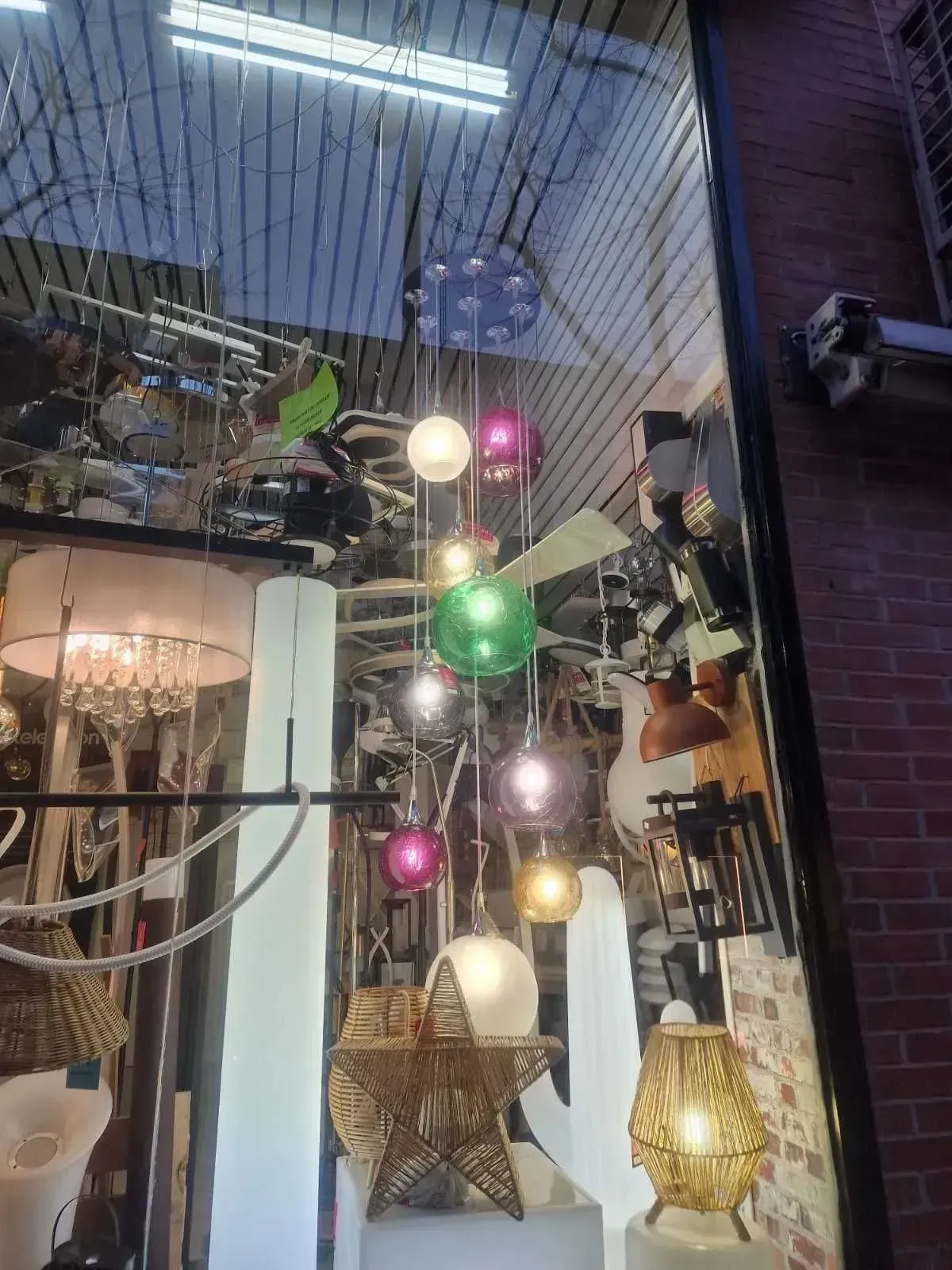 Escaparate de una tienda con diversas lámparas y apliques decorativos colgantes en una habitación bien iluminada.