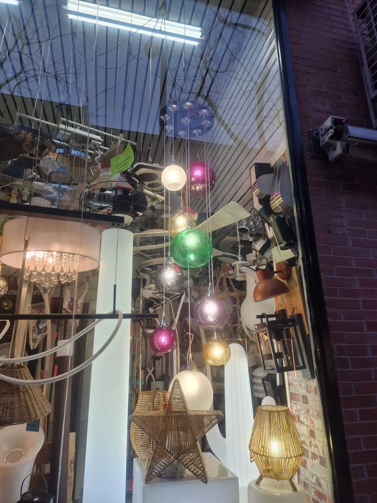 Un escaparate con varias lámparas colgantes esféricas de diferentes colores, lámparas tejidas