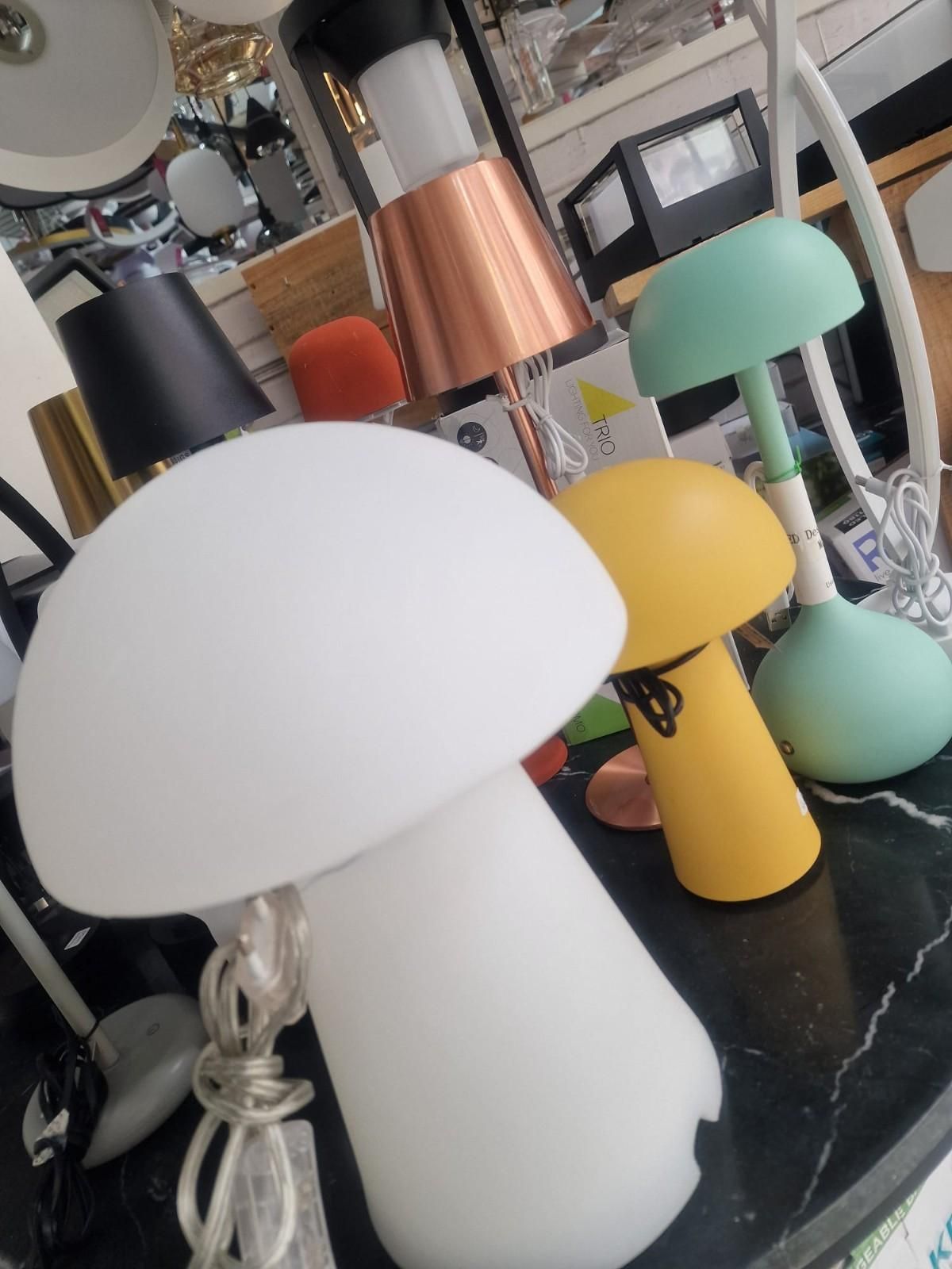 Varias lámparas de mesa con forma de hongo en distintos colores, como blanco, amarillo y verde menta