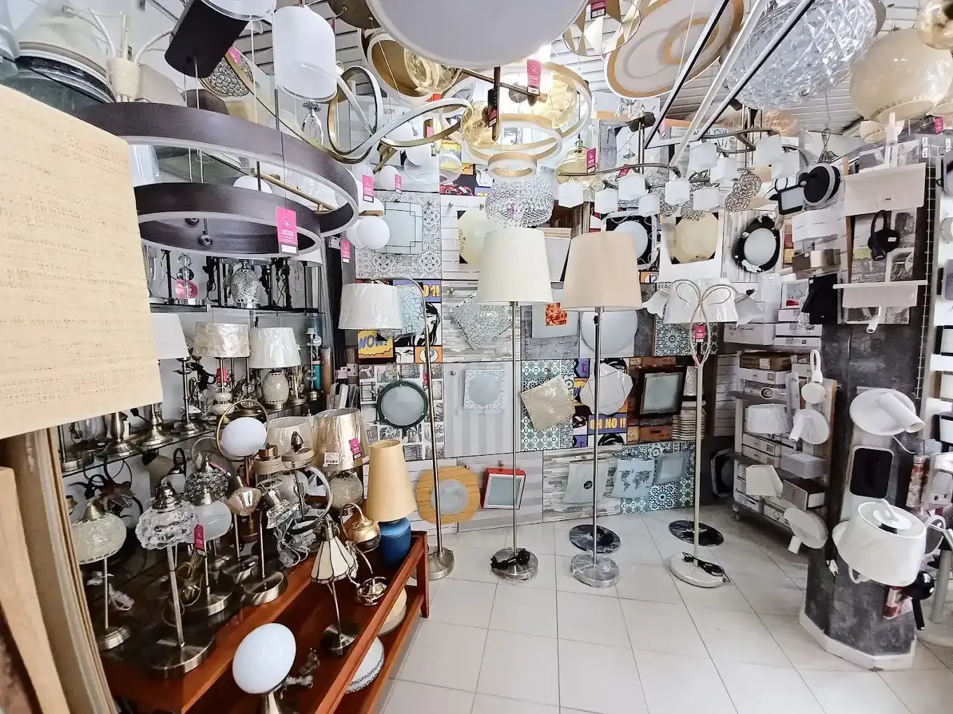 Un escaparate de tienda repleto de una variedad de lámparas colgantes, plafones, lámparas de mesa y lámparas de pie.