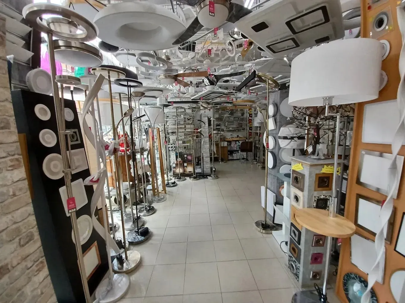 Un pasillo de tienda bien iluminado que exhibe una variada selección de modernas lámparas colgantes y de pie.