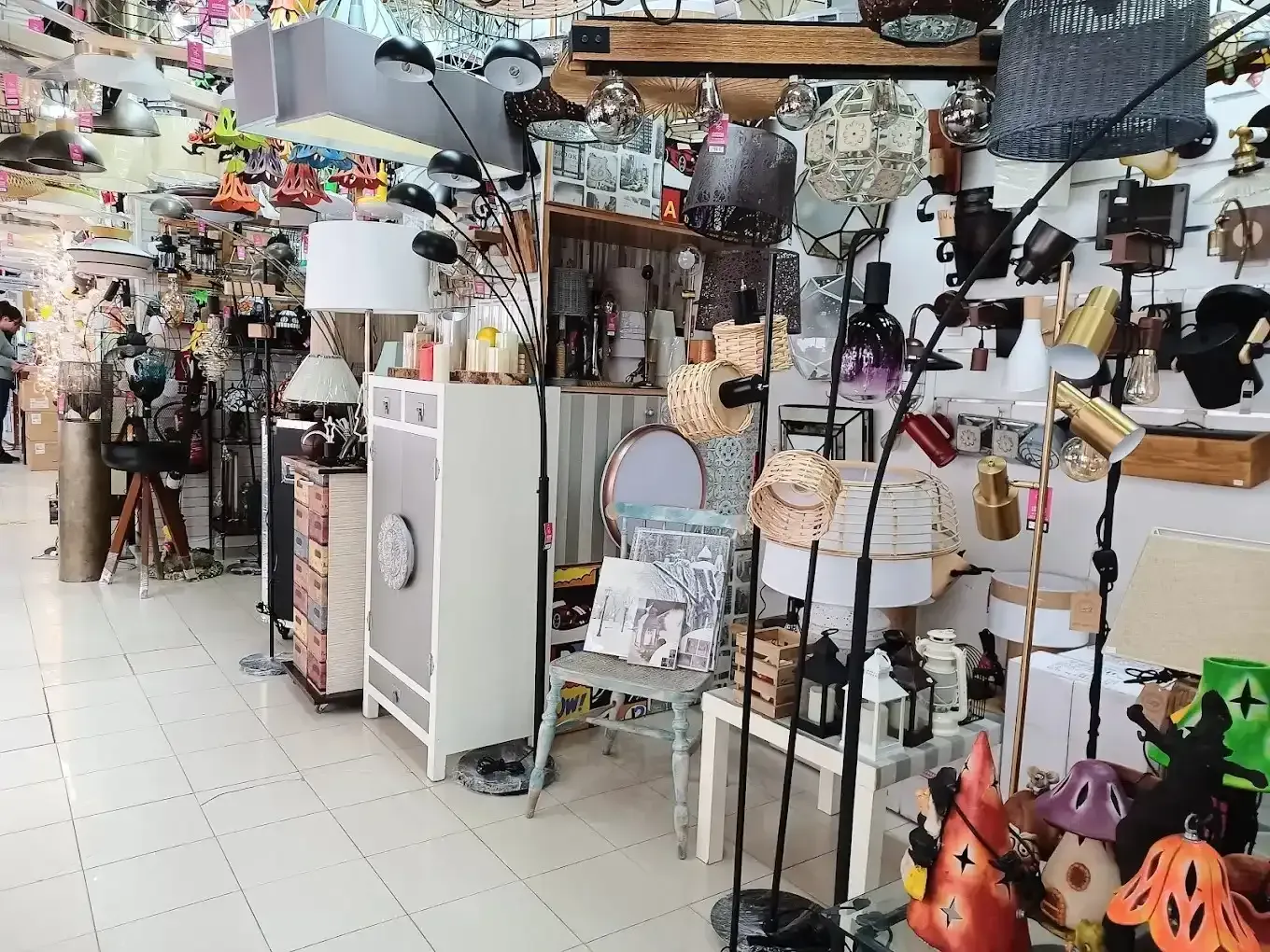 Vista interior de una tienda que exhibe una amplia variedad de lámparas, apliques colgantes y artículos decorativo