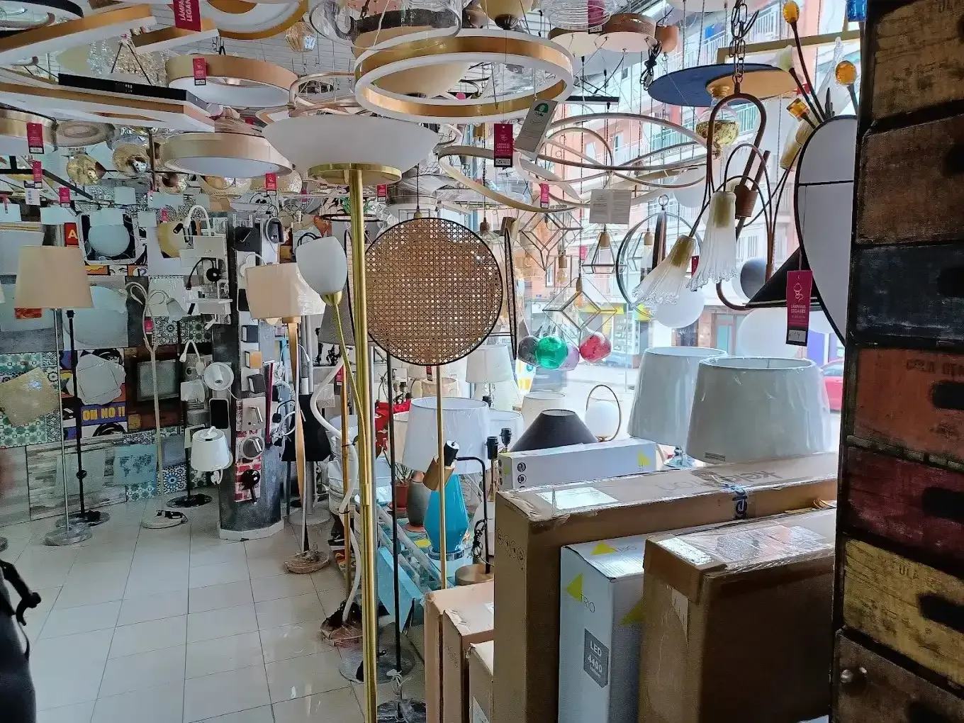 Una tienda minorista repleta de una variedad de lámparas colgantes y de pie en un escaparate luminoso y desordenado.