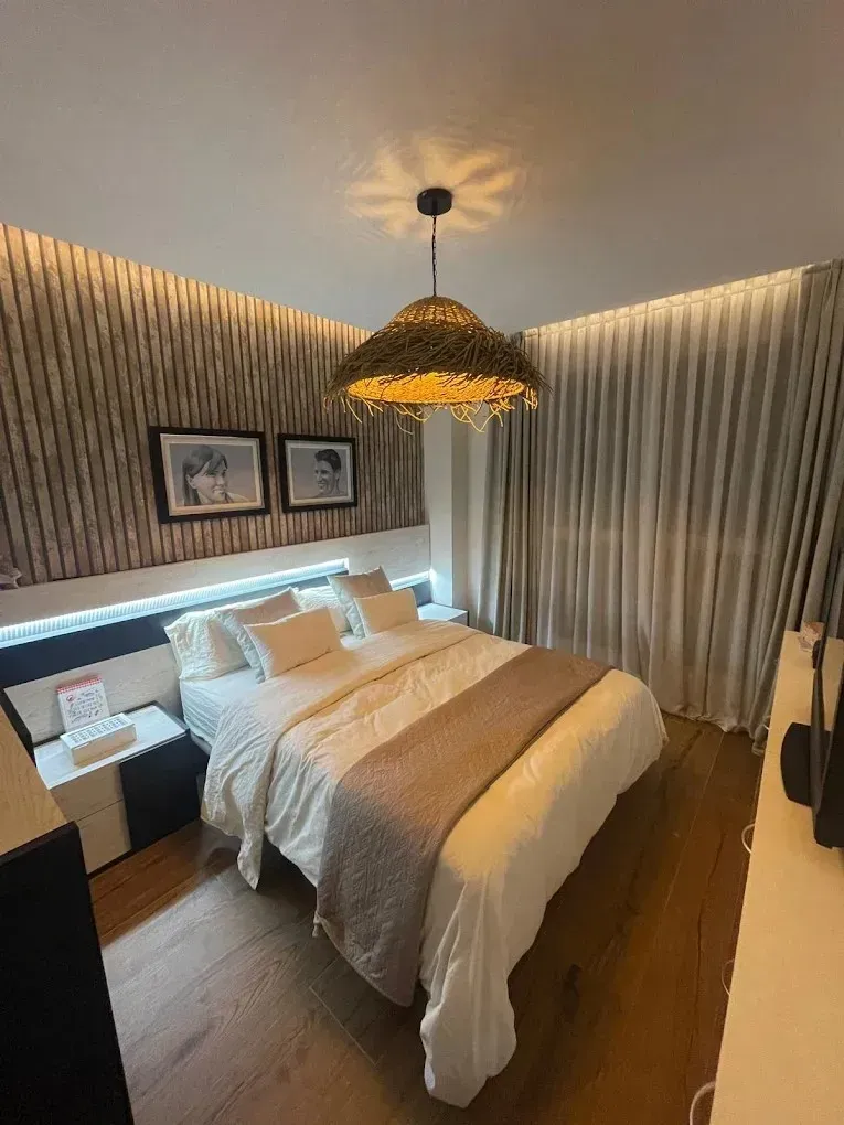 Un dormitorio acogedor y moderno con una cama con ropa de cama blanca, una pared texturizada