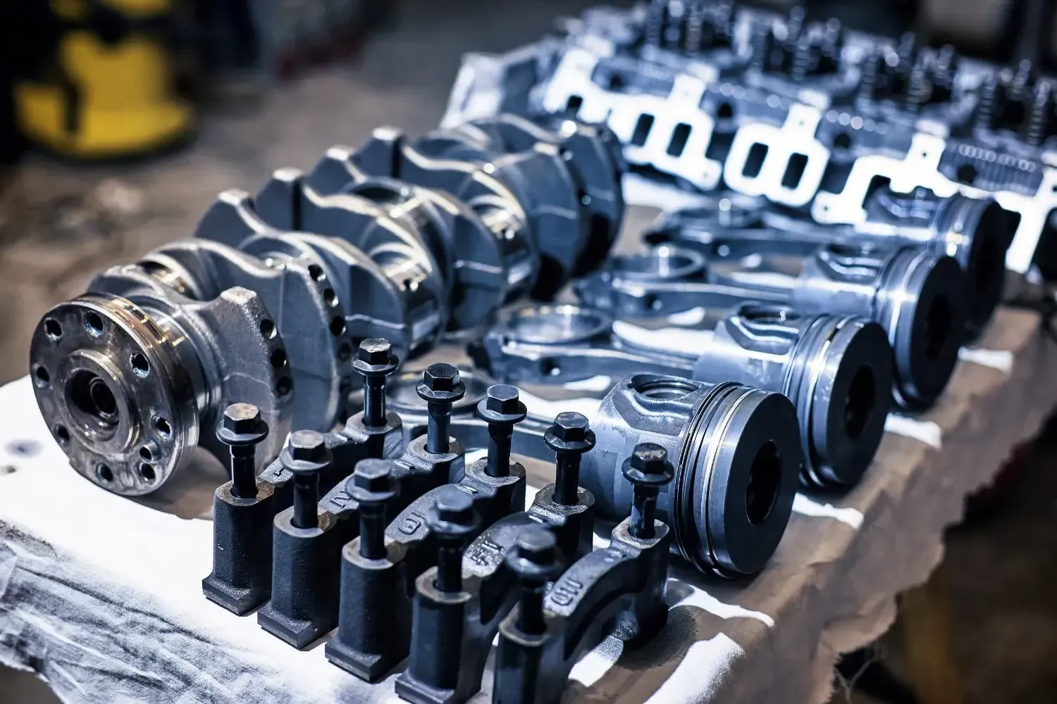 Piezas del motor dispuestas sobre una mesa: cigüeñal, pistones, bielas, culatas, fijaciones.