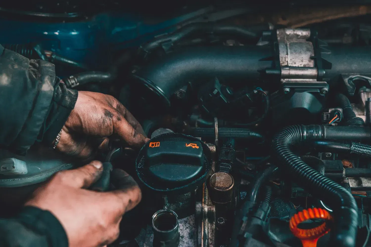 Manos trabajando en un motor de coche, cubierto de aceite y grasa.