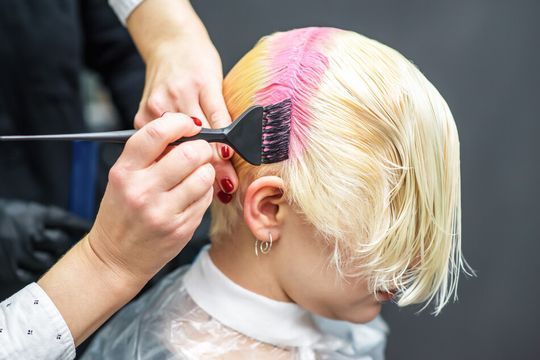 Una mujer se está tiñendo el pelo en un salón.