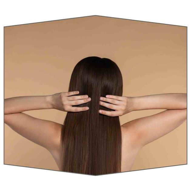 Una mujer con cabello largo sostiene su cabello con sus manos.