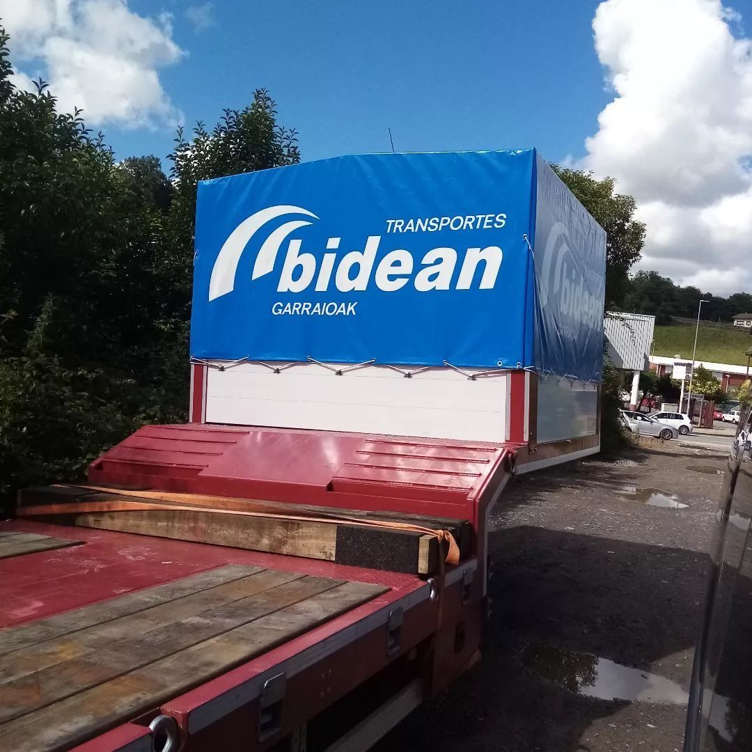 Un camión de plataforma con una gran caja azul rotulada