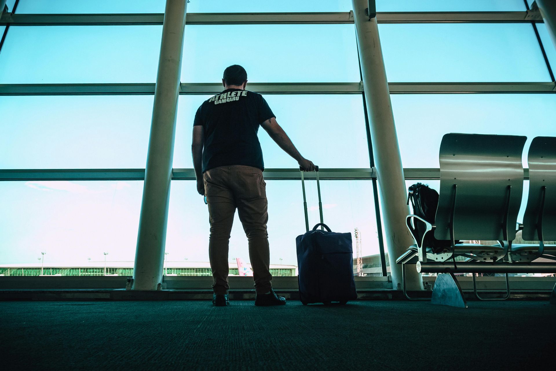 a man standing at the airport with his luggage