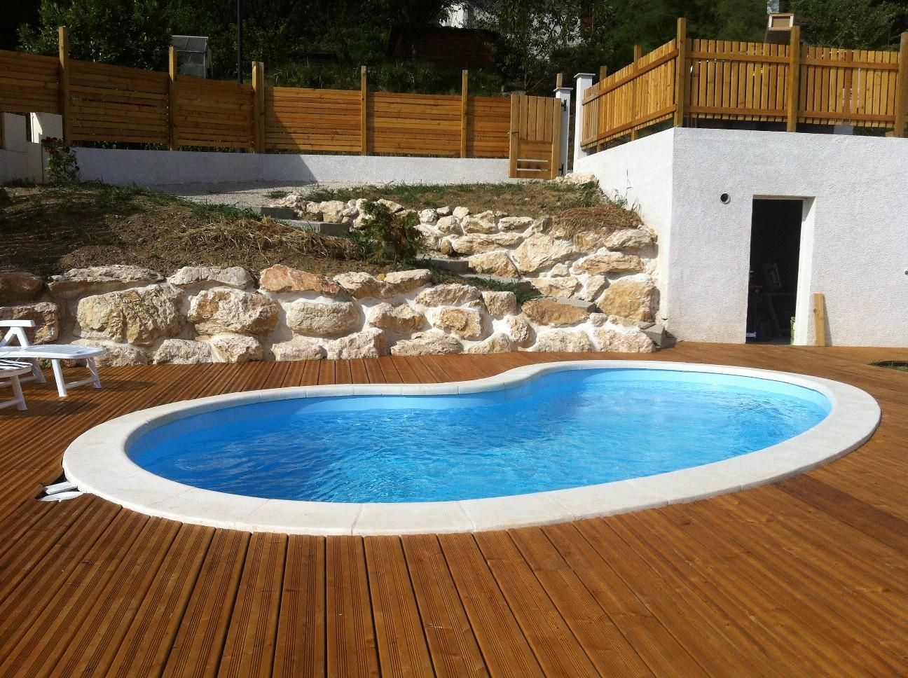 Piscine à coque avec plancher en bois et mur en pierre