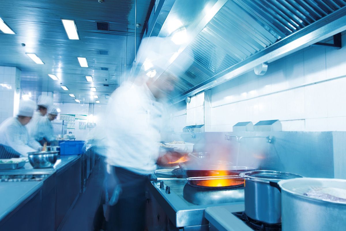 Koch reibt Parmesan auf Teller