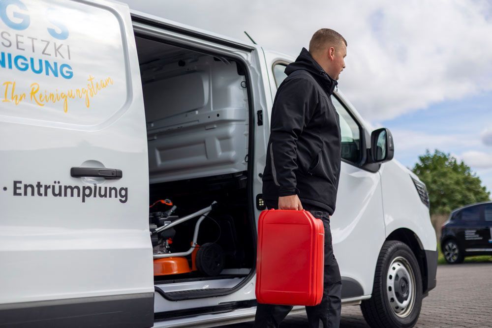 Eine Mitarbeiter trägt einen roten Kanister aus dem Firmenwagen heraus.