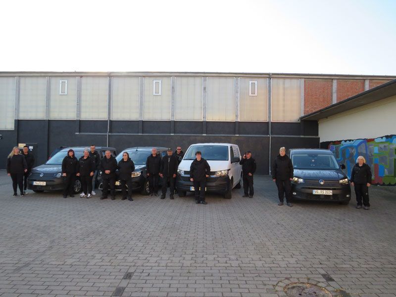 Eine Gruppe von Menschen steht vor einer Reihe von Lieferwagen.