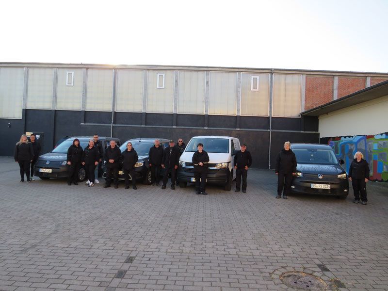 Eine Gruppe von Menschen steht vor einer Reihe von Lieferwagen.