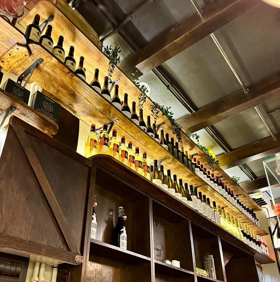 Estantes repletos de botellas de licor se alinean a lo largo del techo y la pared de un bar cálidamente iluminado.