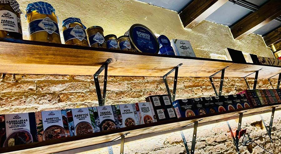Productos envasados ​​colocados en estanterías en un pasillo de tienda bien iluminado, con filas de frascos y cajas sobre estantes de madera.