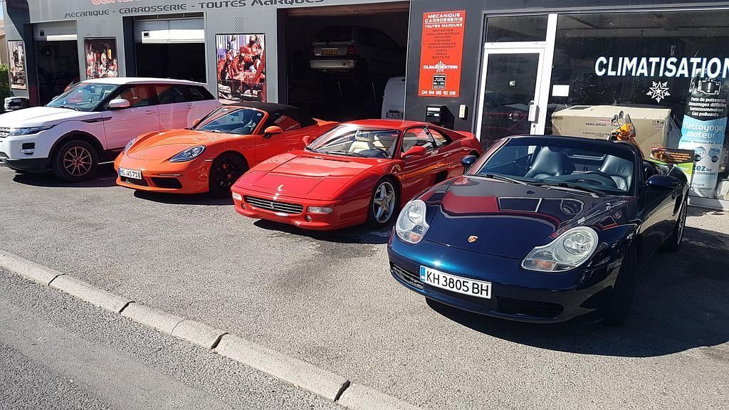 Quatre voitures de sport garées devant une boutique, dont des coupés rouges, orange et bleus.