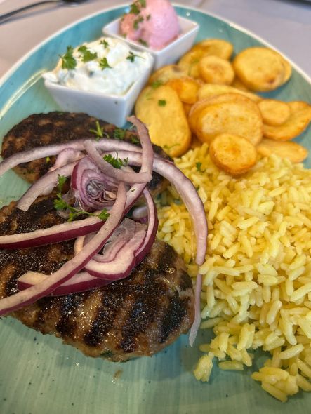 Gegrilltes Steak mit roten Zwiebeln, gelbem Reis, gebratenen Kochbananen und Salsa auf einem Teller