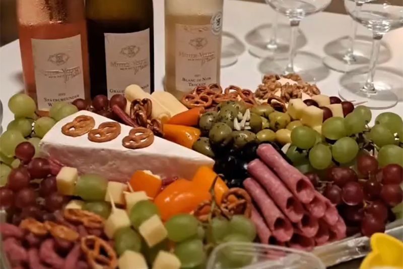 Eine Wurstplatte mit Trauben, Käse, Oliven, Fleisch und Crackern auf einem Tisch bei einem Treffen