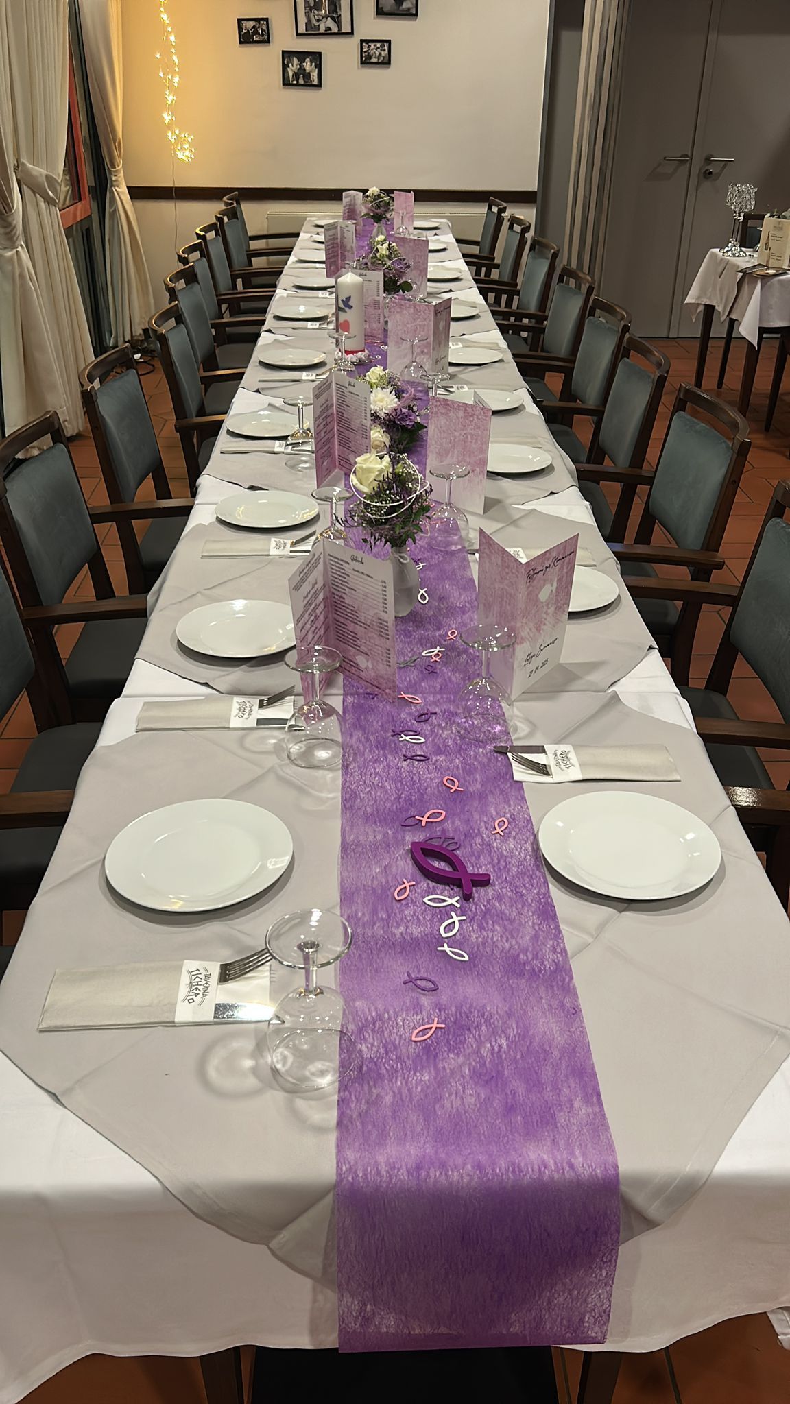 Eine Festtafel mit weißen Tellern, violetten Tischläufer und Tischdekorationen in einem festlich geschmückten Esszimmer.