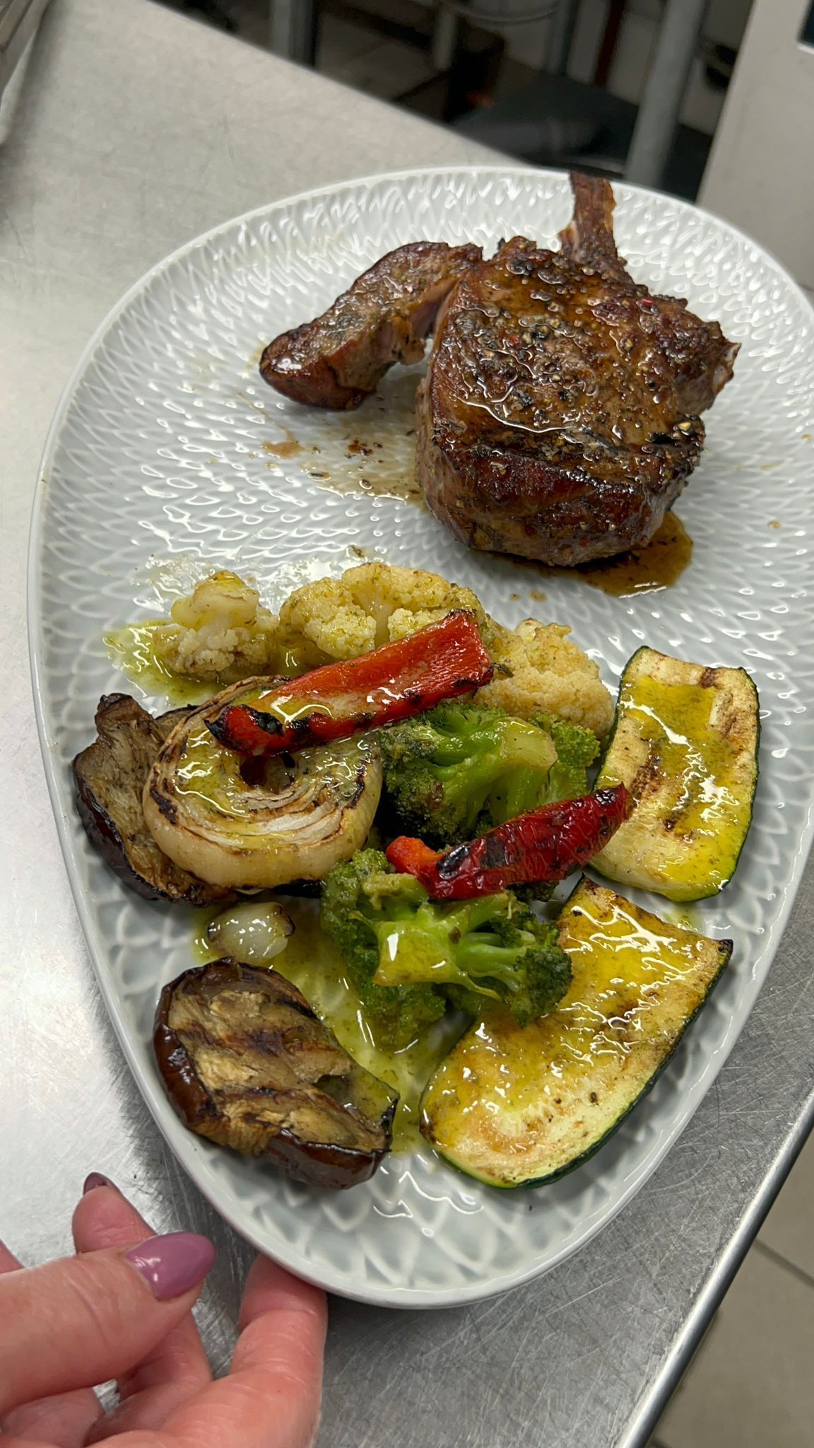 Gegrilltes Fleisch mit geröstetem Gemüse, darunter Paprika, Zucchini und Champignons, auf einem Teller angerichtet.