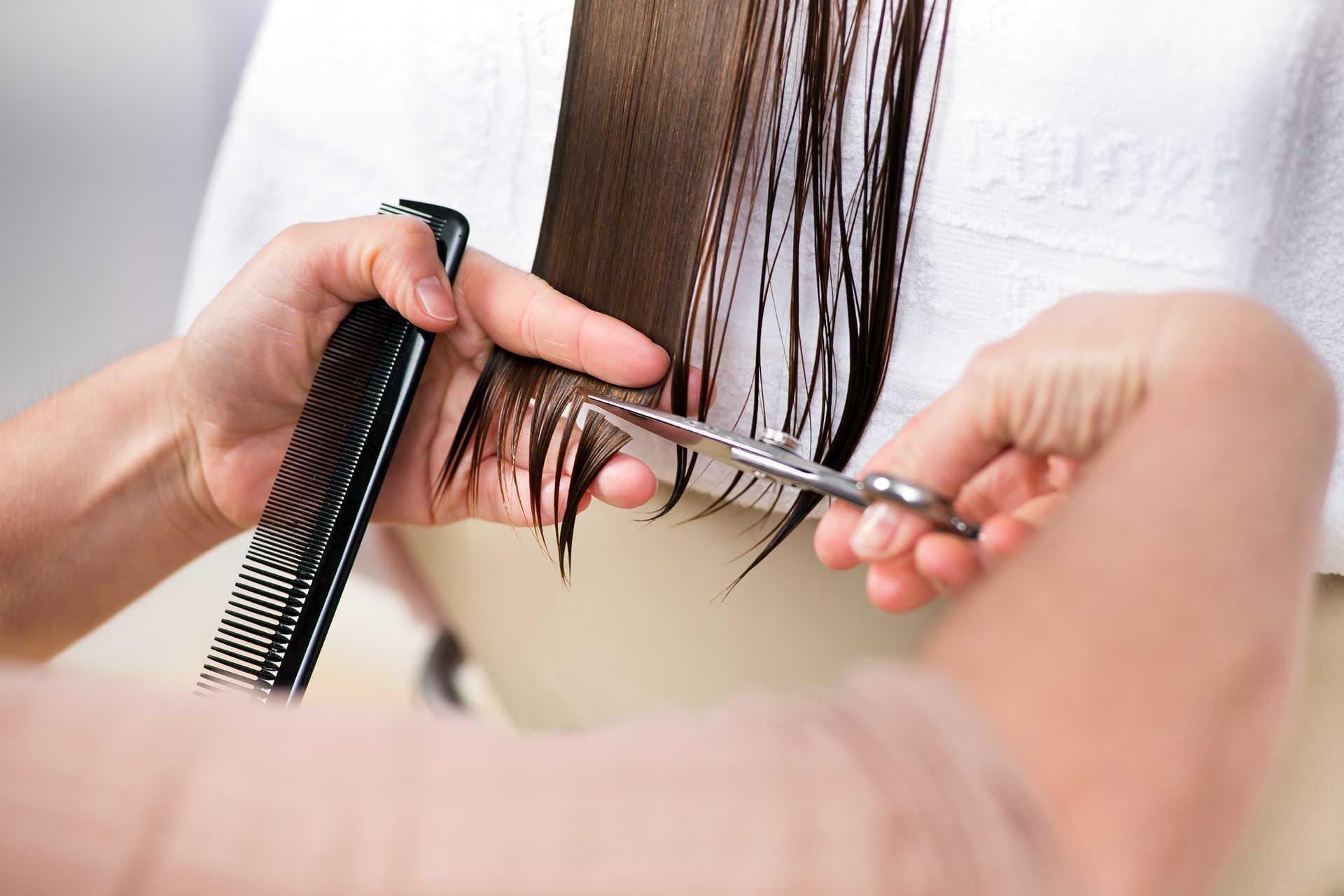 Friseur schneidet nasses Haar mit Schere und Kamm.