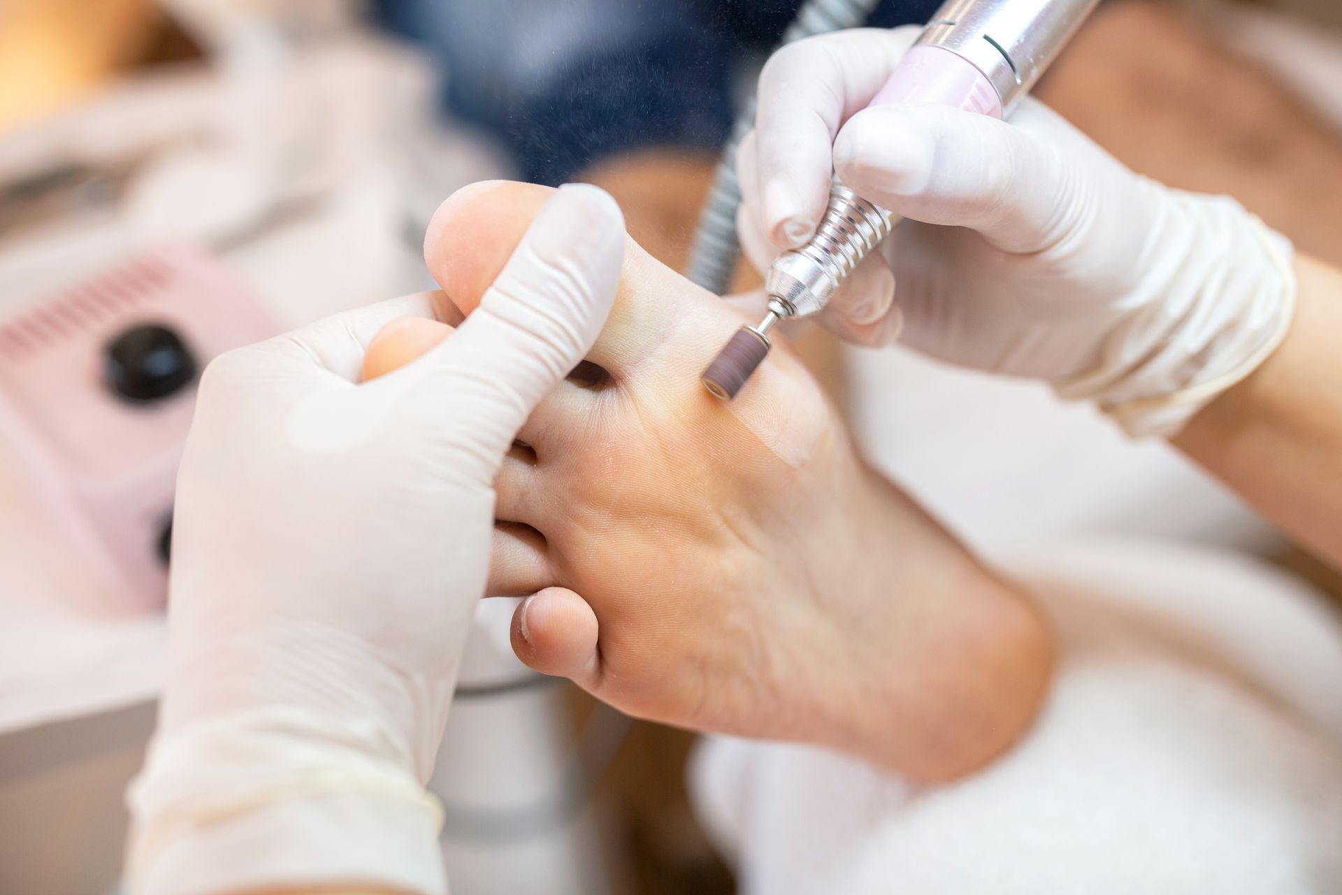 Behandschuhte Hände, die während einer Maniküre einen Nagelfräser an der Hand einer Person benutzen