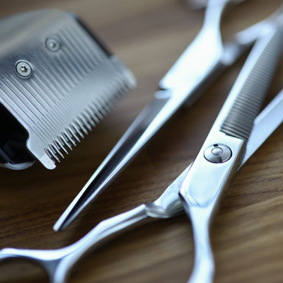 Silberne Schere und ein Haarschneidekamm auf einer Holzoberfläche, Nahaufnahme.