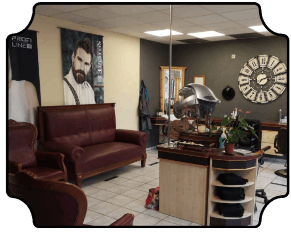 Wartebereich des Salons mit bordeauxroten Stühlen, Empfangstresen, Wanduhr und gerahmtem Porträt
