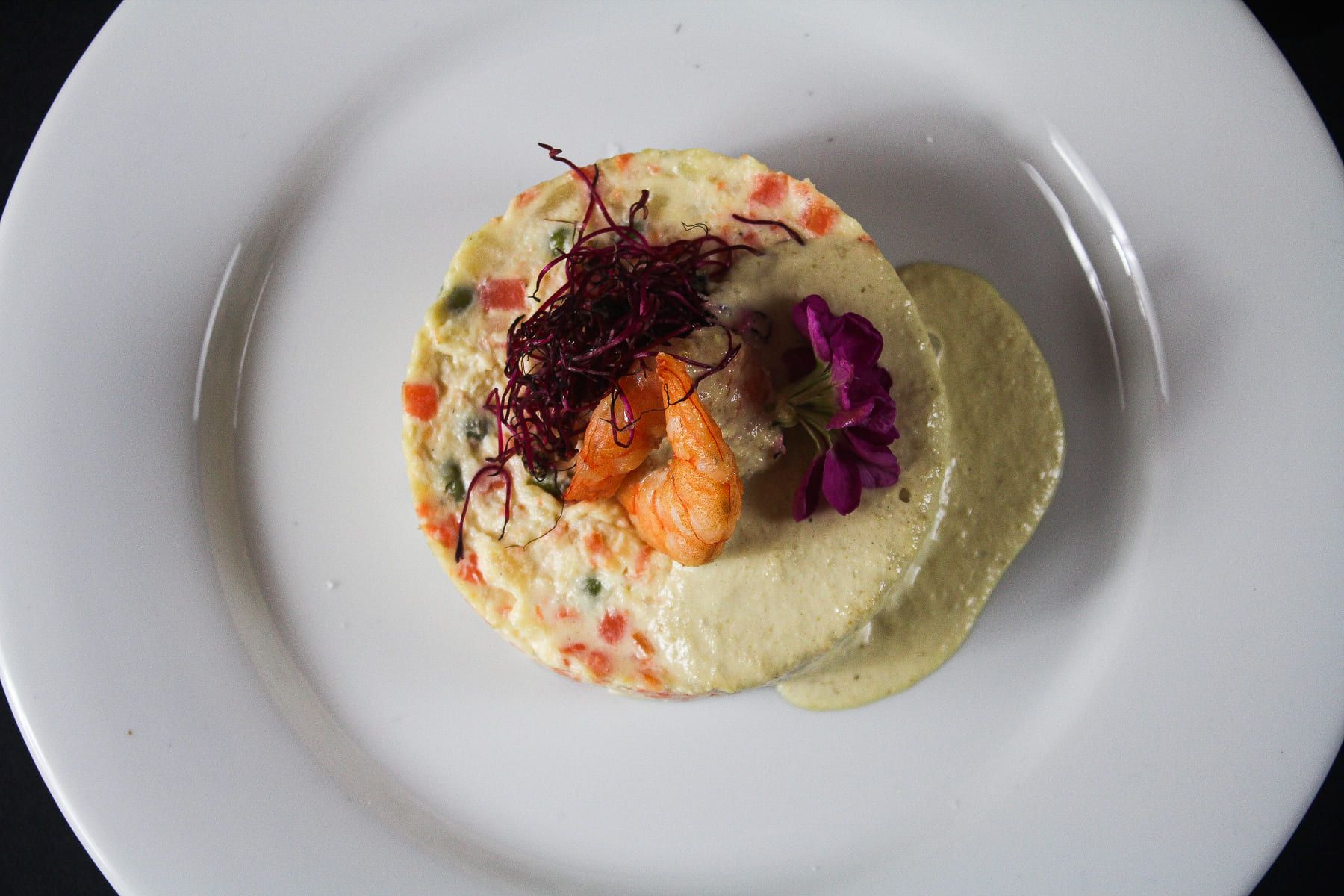 Un plato blanco cubierto con una salsa blanca y verduras.