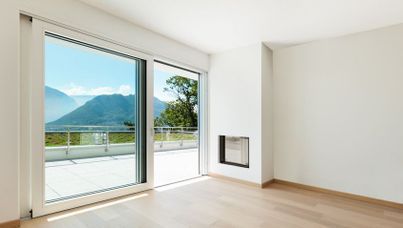 Habitación moderna vacía con gran puerta corrediza de vidrio, balcón y vista a la montaña.