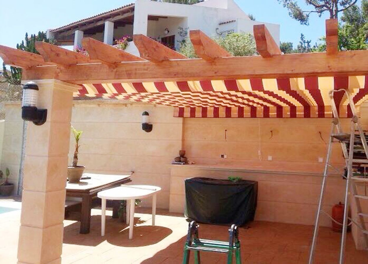 Pérgola con toldo de rayas sobre patio con mesa y sillas.