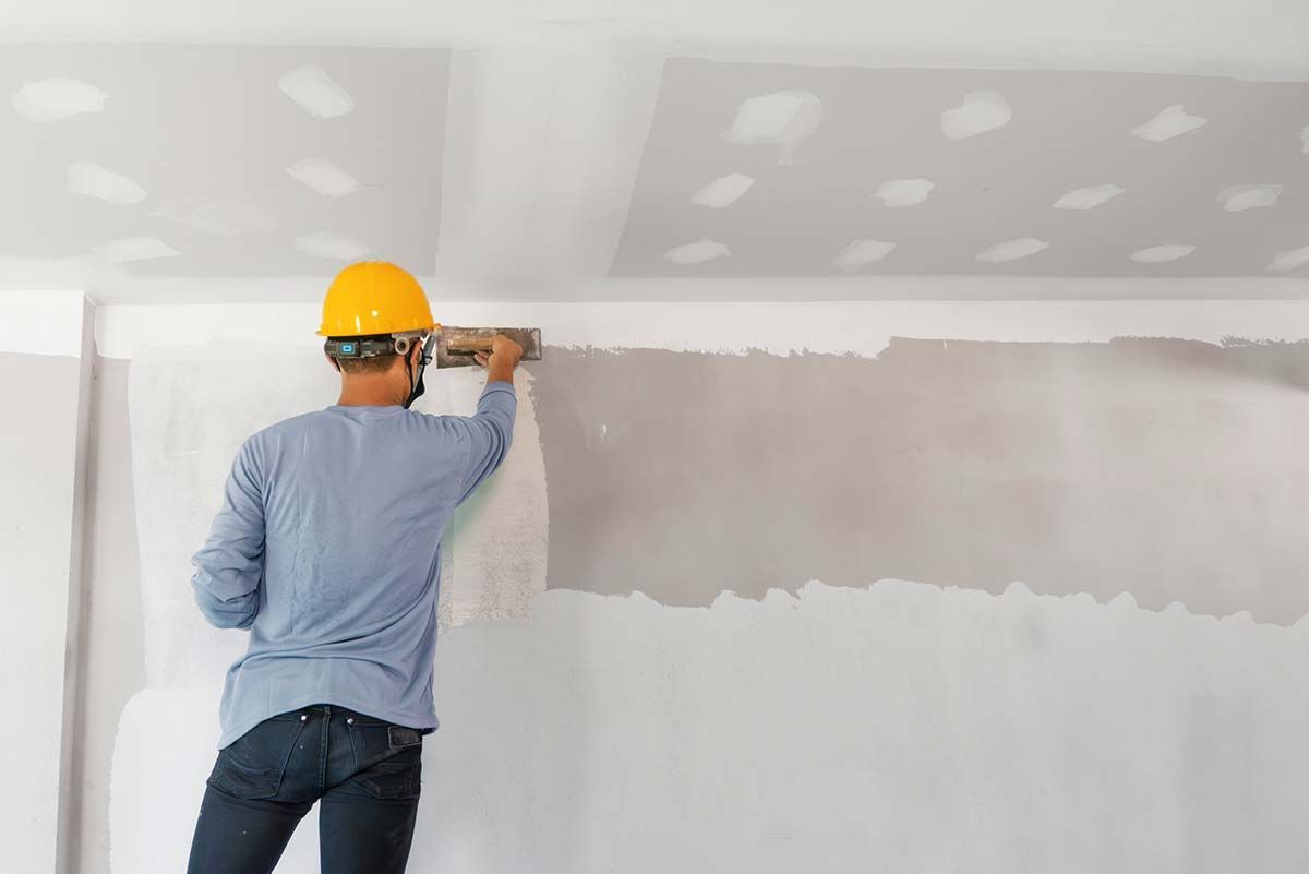 Un hombre que lleva un casco está enyesando una pared.