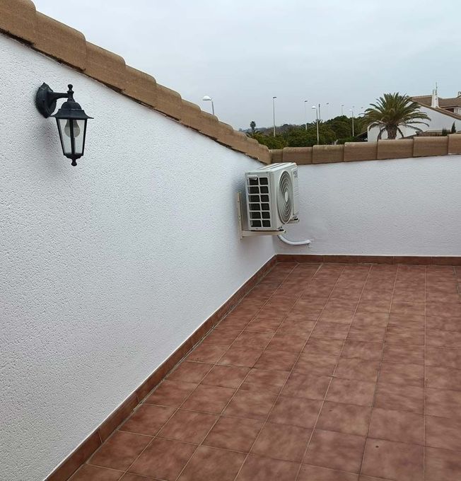 Una pared blanca con una lámpara y un ventilador encima.