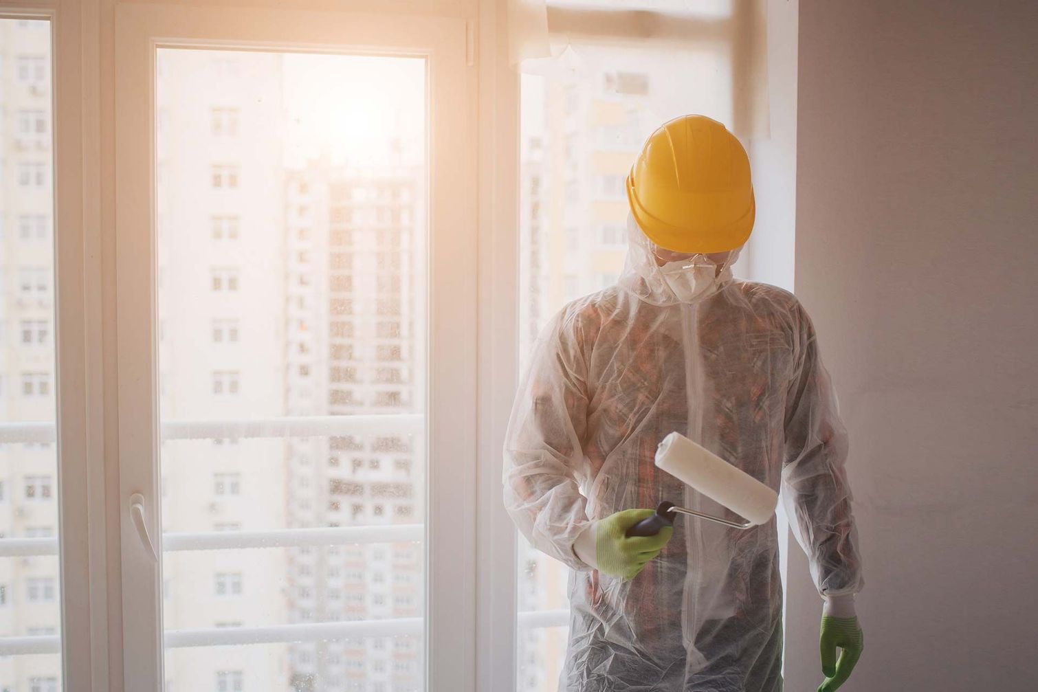 Un hombre con casco y traje de protección sostiene un rodillo de pintura.