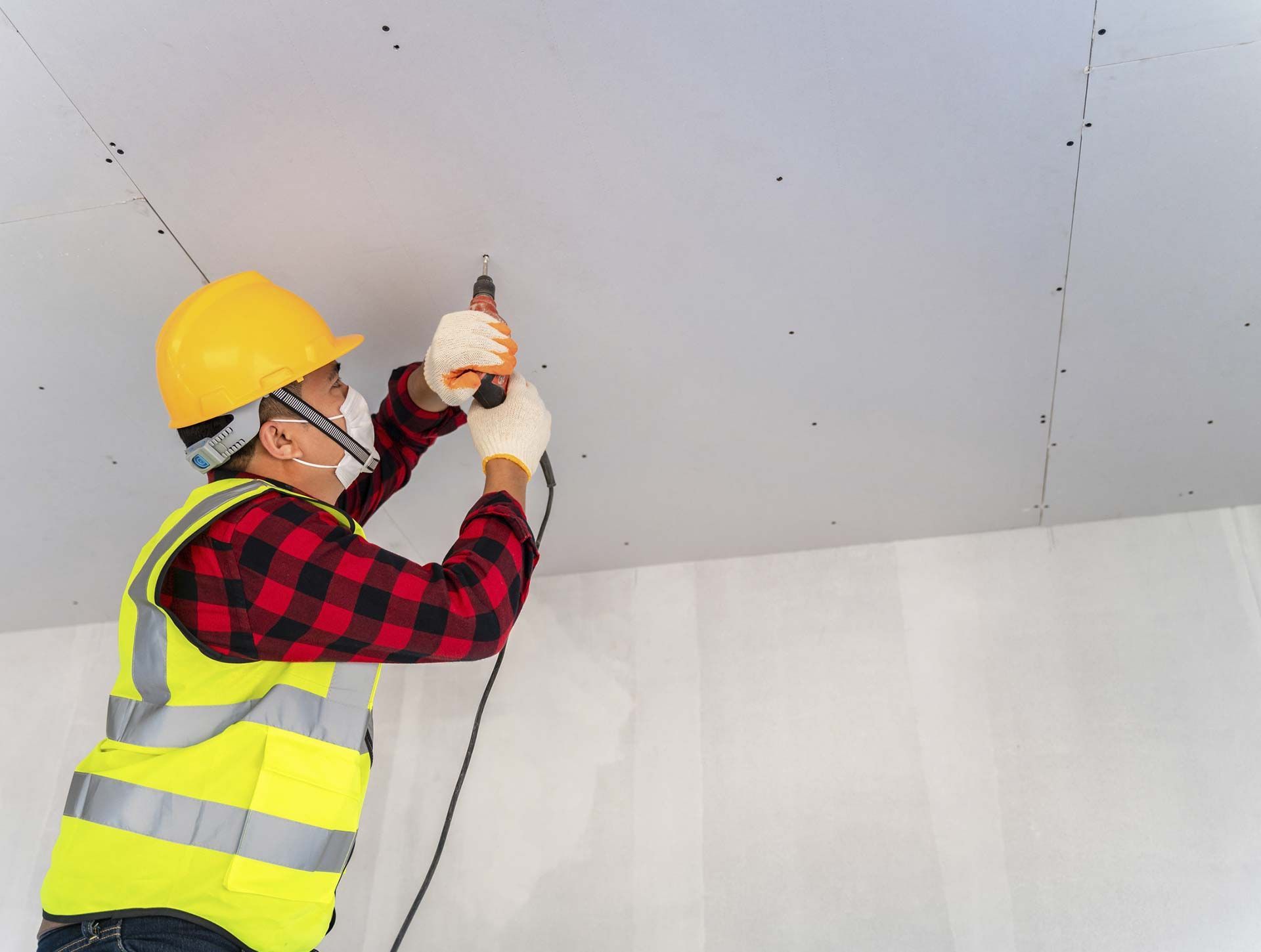 Un trabajador de la construcción está trabajando en un techo con un taladro.