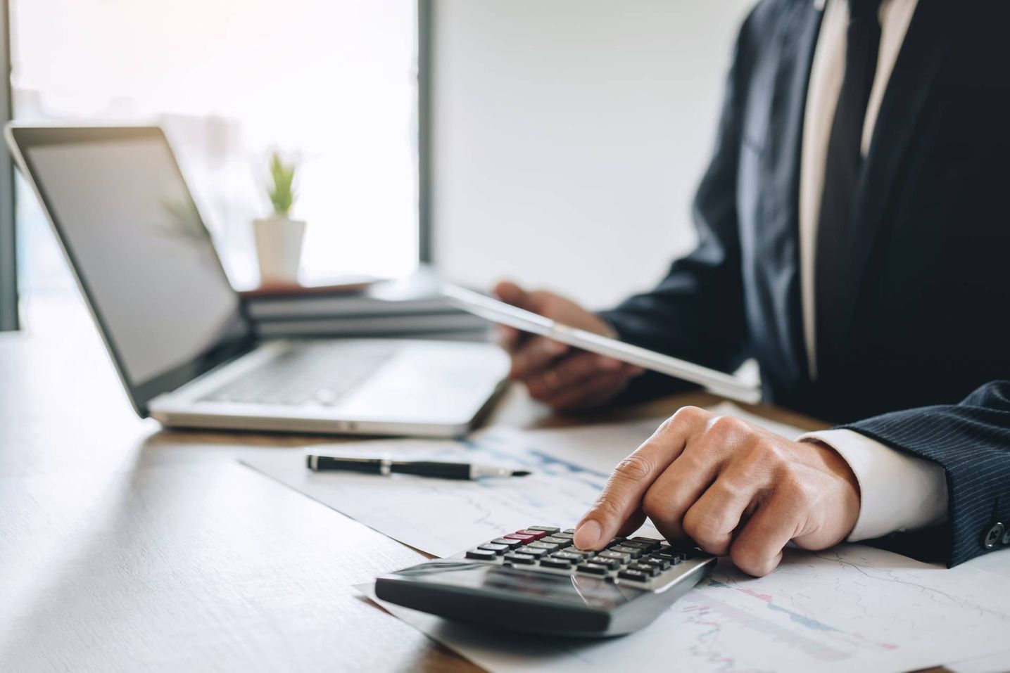 Mann tippt etwas in den Taschenrechner