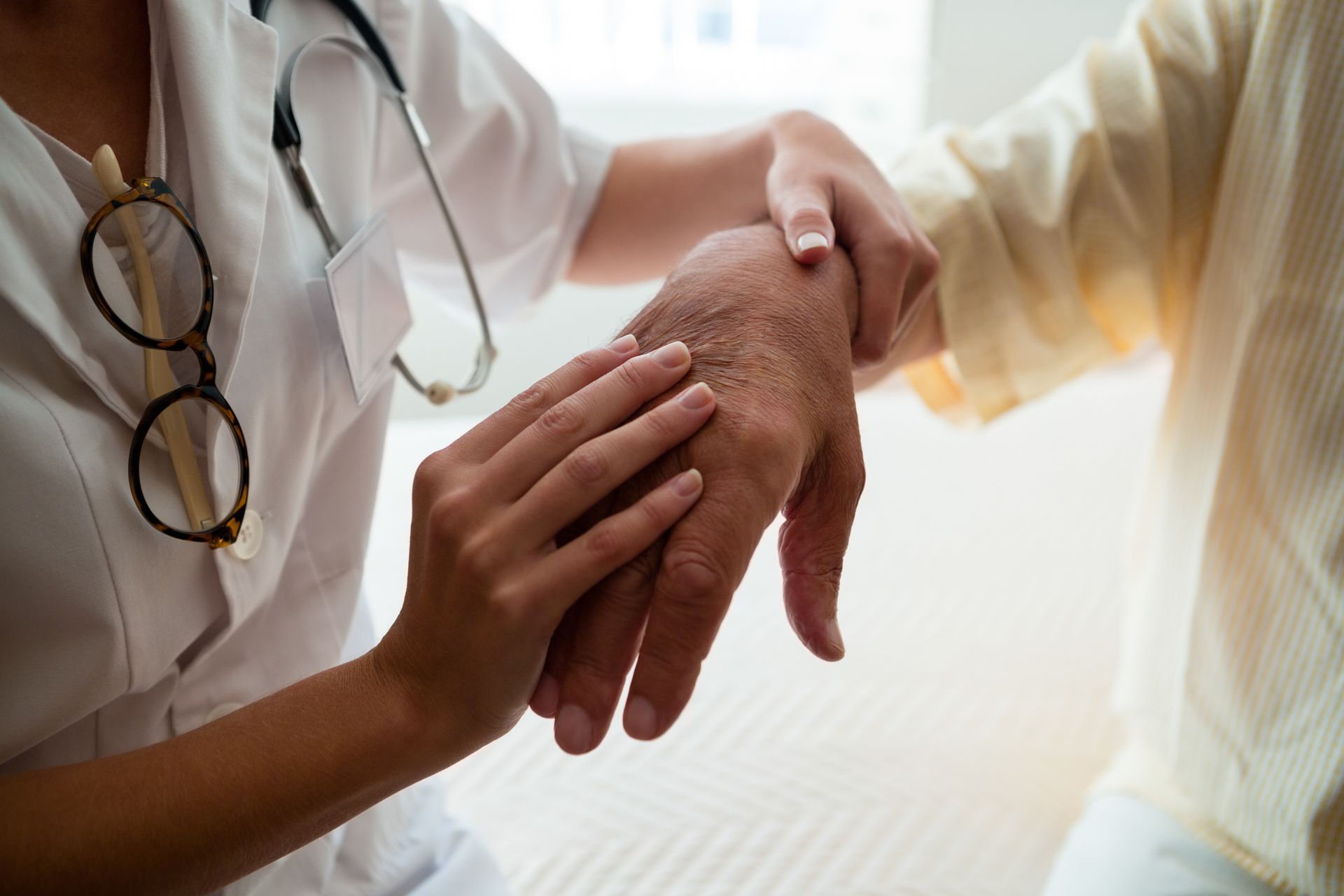 Un médecin tient doucement la main d'un patient lors d'une consultation médicale.