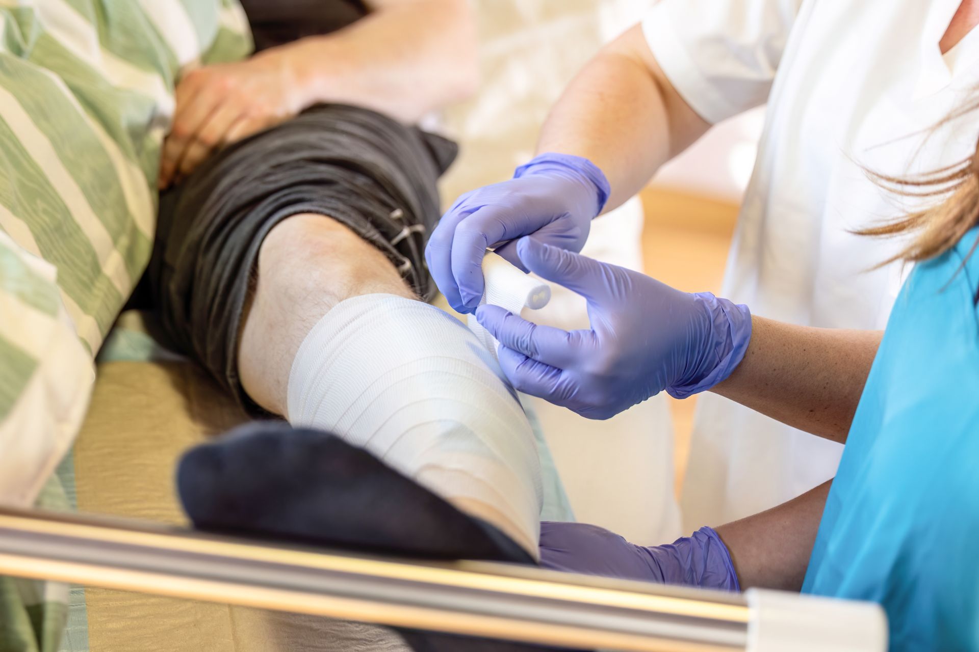 Personnel médical appliquant un bandage à la jambe d'un patient alité dans un hôpital