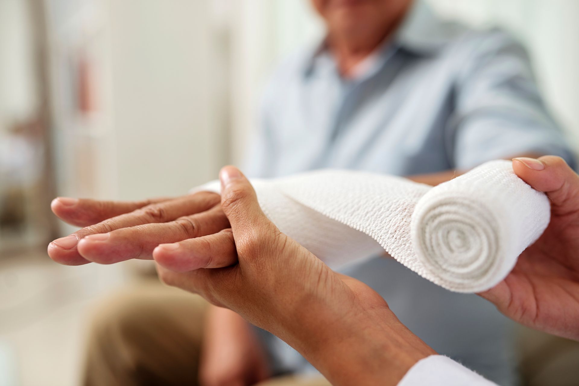 Une main reçoit un bandage blanc roulé dans un environnement clinique