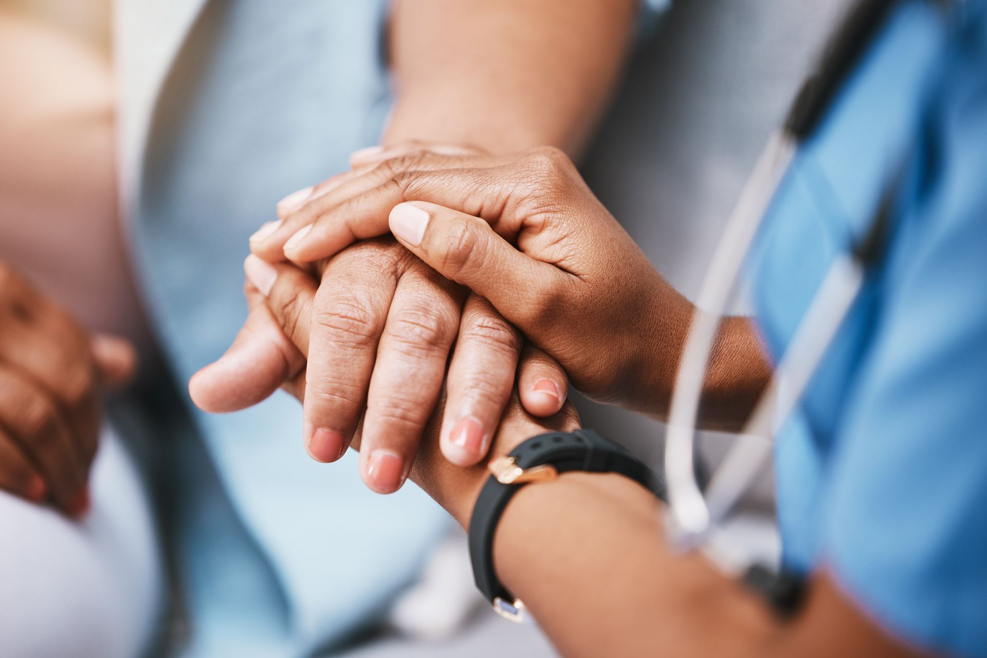 Mains jointes dans un geste de soutien, un stéthoscope visible dans un contexte médical