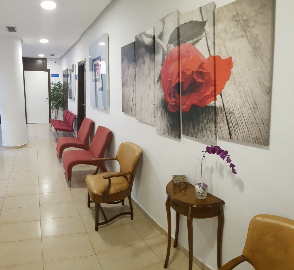 Pasillo con zona de espera; sillas de varios colores y obras de arte.