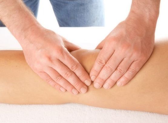 Manos masajeando la rodilla de una persona; la persona está acostada.