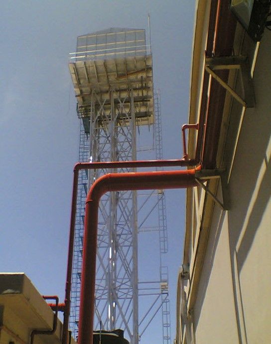 a tower with a ladder on top of it is surrounded by red pipes