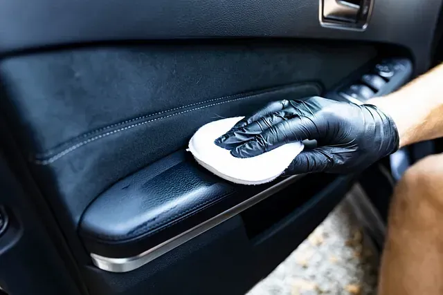 Una persona que lleva guantes negros está limpiando la manija de la puerta de un automóvil.