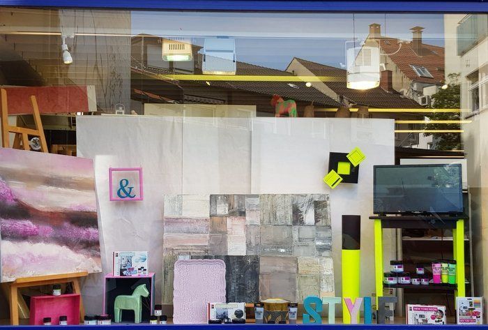 Ein Schaufenster mit einem Gemälde an der Wand und einem Fernseher auf einem Ständer.