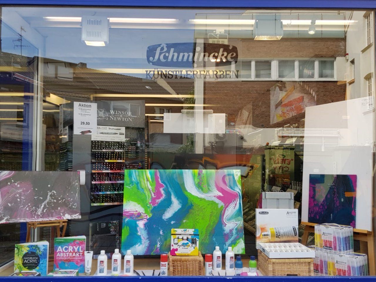 In einem Schaufenster ist ein farbenfrohes Gemälde ausgestellt.
